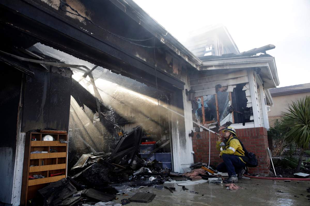 Calib Willis of the Los Angeles County Fire Department hoses down a smouldering residence destroyed by a wildfire Friday, Oct. 25, 2019, in Santa Clarita, Calif.