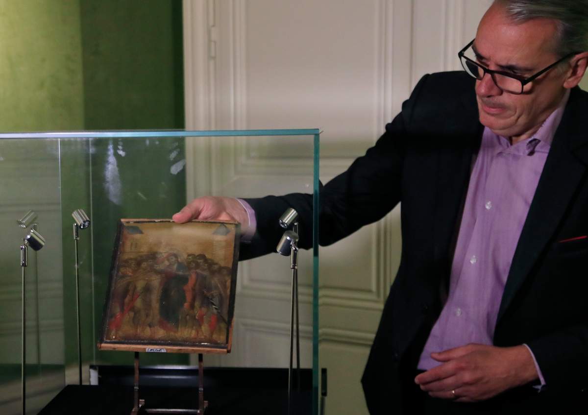 In this Tuesday, Sept. 24, 2019 filer, art expert Stephane Pinta takes out of a glass case a painting by Italian master Cimabue in Paris.