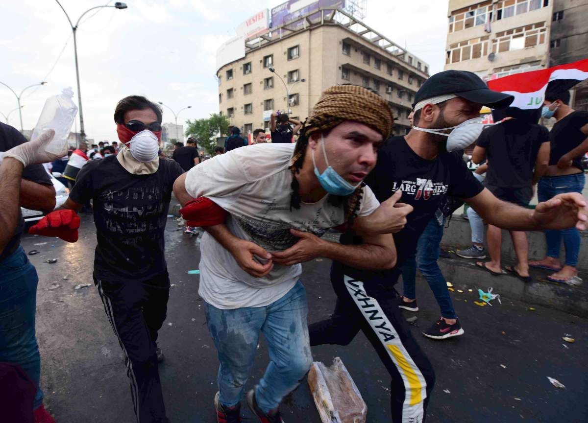 Iraqi protesters help a man who was injured during clashes with Iraqi riot forces following a demonstration at al-Tahrir square, central Baghdad, Iraq, 27 October 2019.
