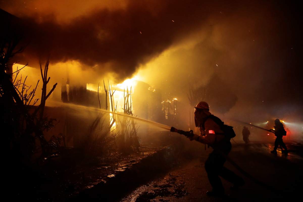 Firefighters try to hose down flames as homes burn in the Getty fire area along Tigertail Road, Monday, Oct. 28, 2019, in Los Angeles. (AP Photo/Marcio Jose Sanchez)