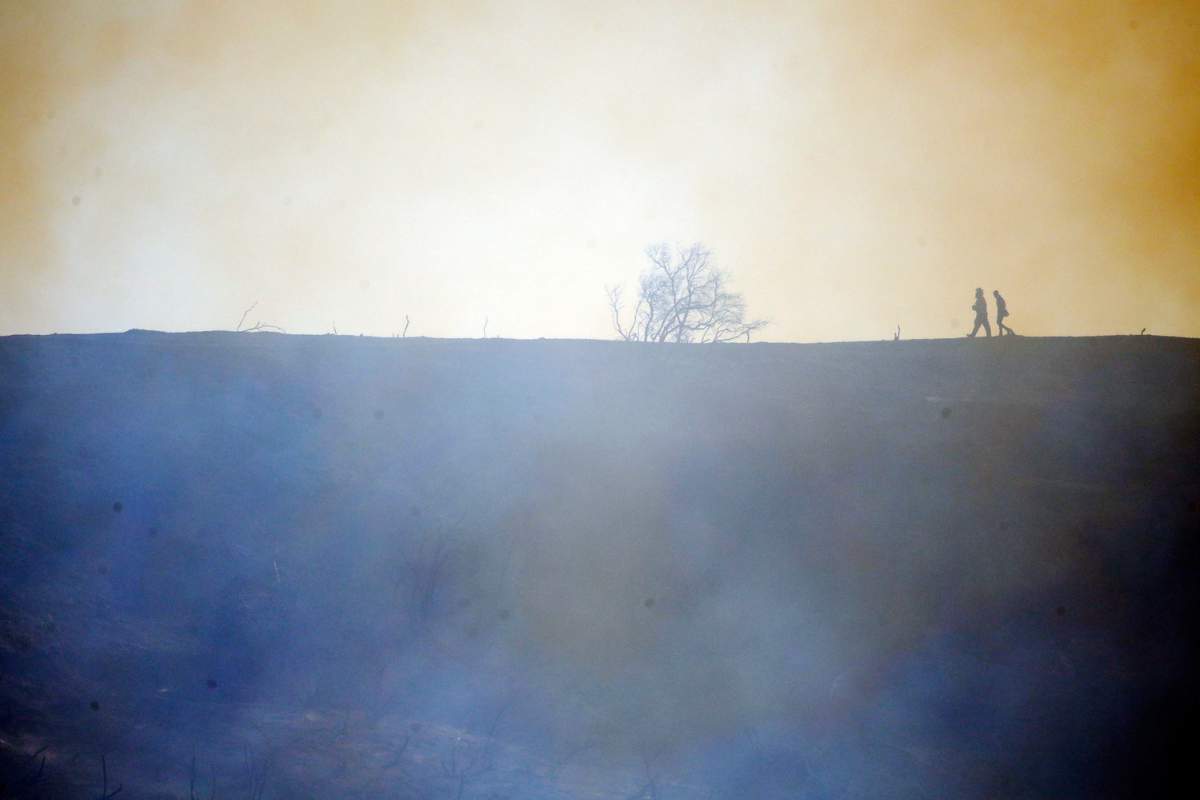 Firefighters walk on top of a burned down canyon caused by the Getty fire in Mandeville Canyon on Monday, Oct. 28, 2019, in Los Angeles. (AP Photo/Marcio Jose Sanchez)