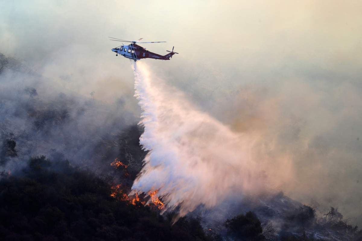 A helicopter drops water as the Getty fire burns in Mandeville Canyon on Monday, Oct. 28, 2019, in Los Angeles. (AP Photo/Marcio Jose Sanchez)