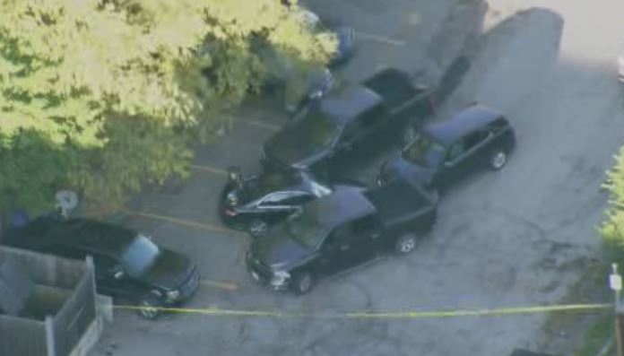 A car is surrounded by vehicles and police tape in an Etobicoke parking lot.