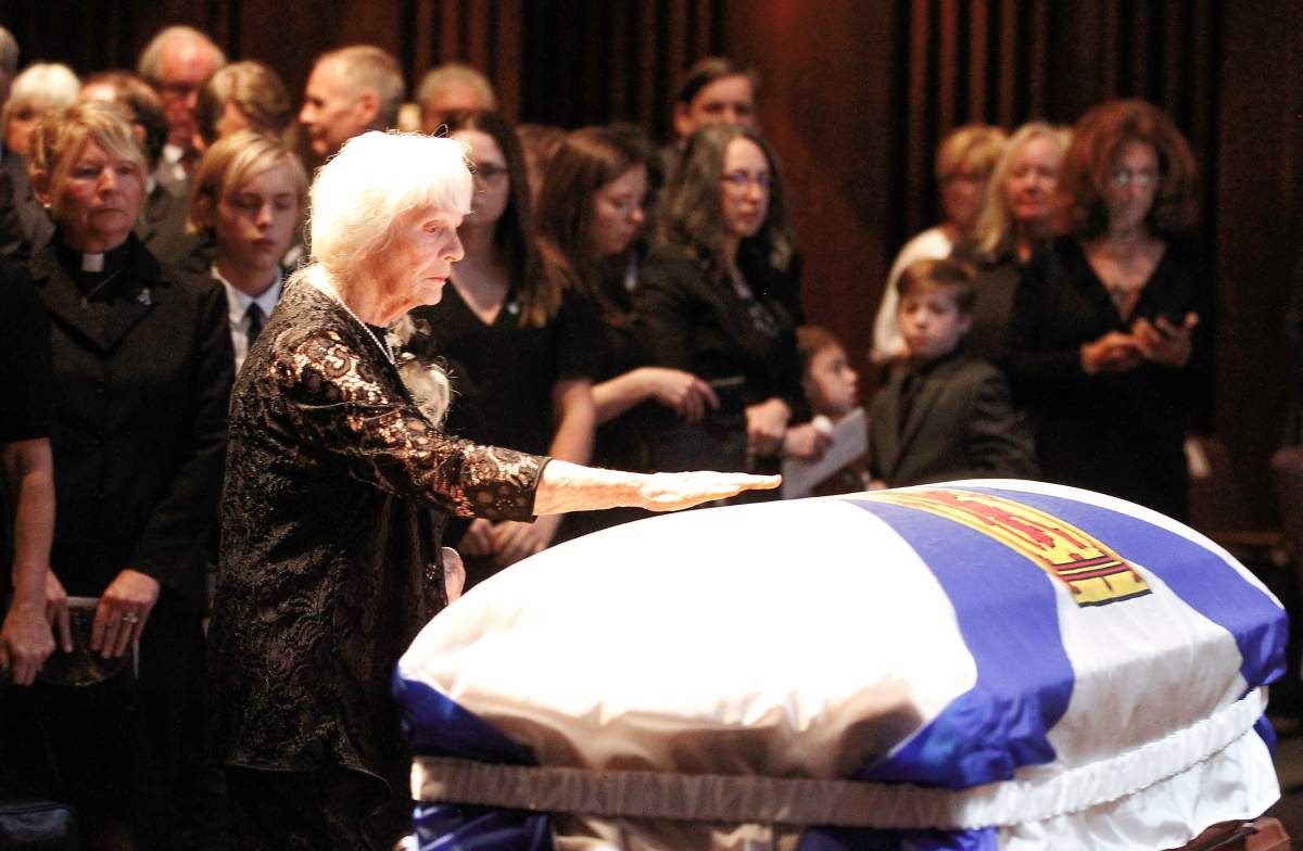 Mavis Buchanan reaches for the casket of her husband John Buchanan at the celebration of the former Nova Scotia premier on Oct. 11, 2019.