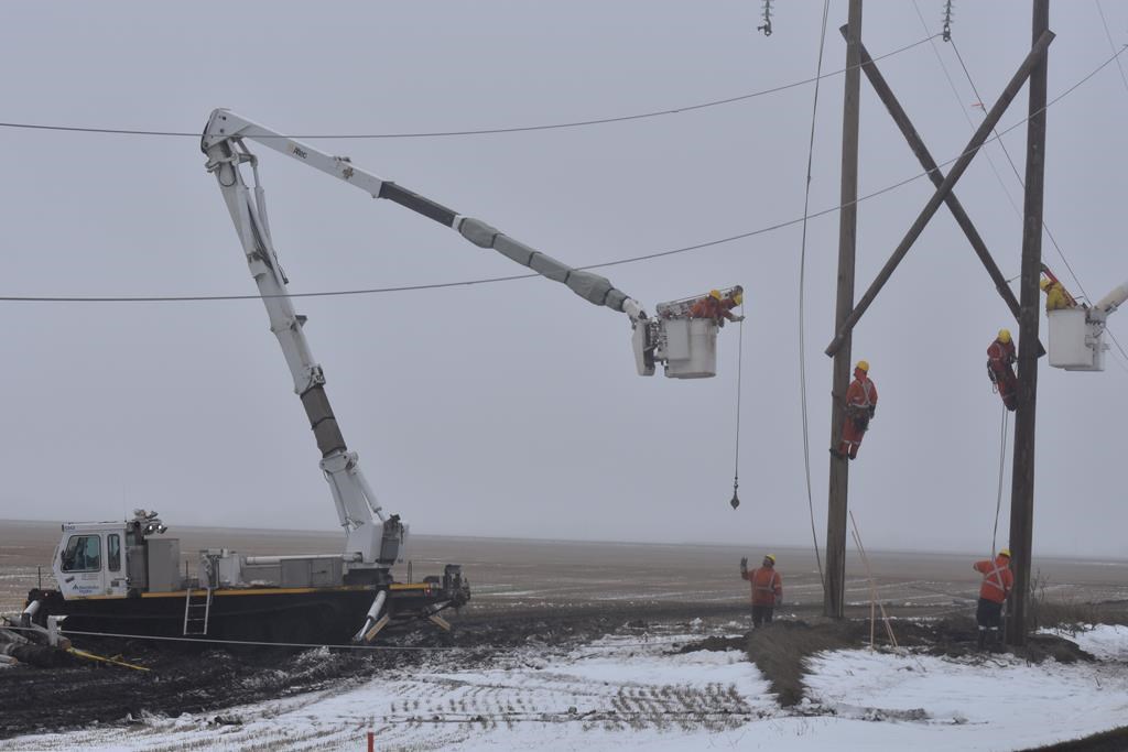 Workers use a tracked vehicle to repair a damaged hydro pole in Portage La Prairie, Man., in a Tuesday, Oct. 15, 2019.