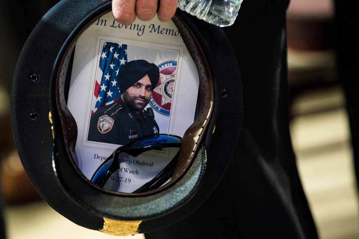 A Houston police officer places a picture of Harris County Sheriff's Deputy Sandeep Dhaliwal in his hat during the deputy's funeral at Berry Center on Wednesday, Oct. 2, 2019, in Houston, Texas. Dhaliwal was killed in the line of duty on Friday.