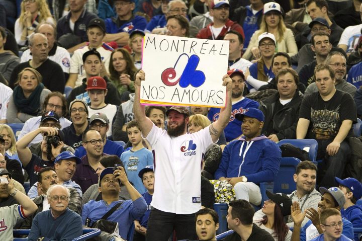 Fans wear Montreal Expos uniforms as they watch the Toronto Blue Jays in a pre-season baseball game against the New York Mets on Friday, March 28, 2014 in Montreal.