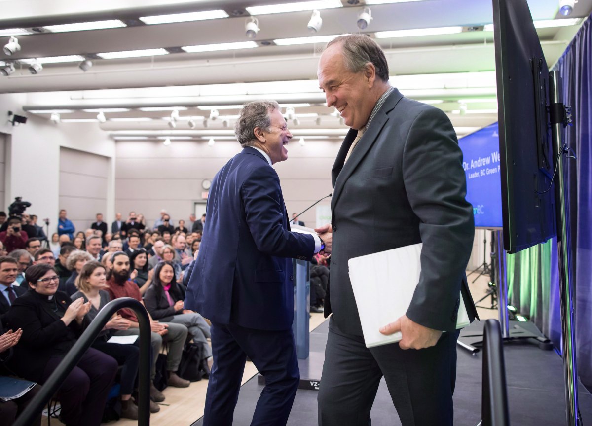 B.C. Minister of Environment and Climate Change Strategy George Heyman, left, shakes hands with Green Party Leader Andrew Weaver as he walks to the podium and Weaver returns to his seat after the provincial government released its CleanBC plan aimed at reducing climate pollution, in Vancouver, on Wednesday December 5, 2018.
