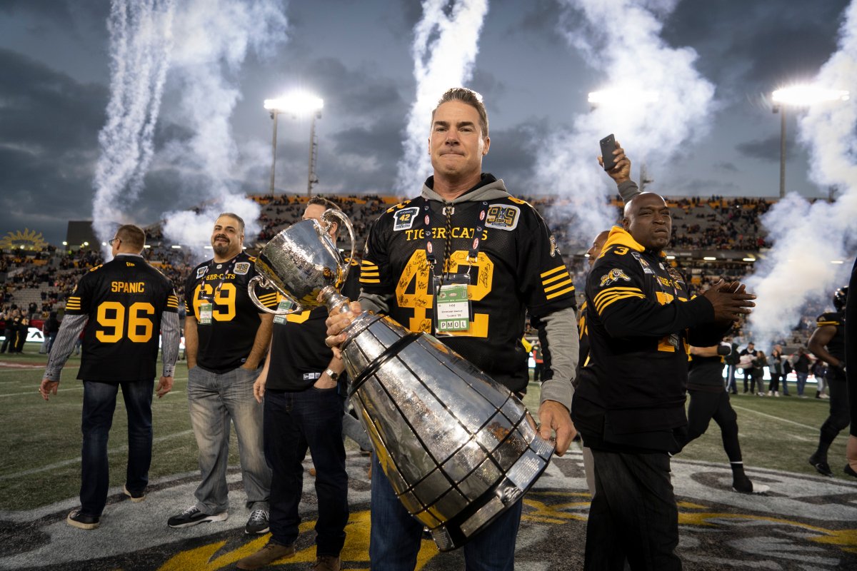 Rob Hitchcock holds the Grey Cup during a pre-game ceremony prior to CFL football game action between the Hamilton Tiger Cats and the Edmonton Eskimos in Hamilton, Ont., Friday, Oct. 4, 2019. Members of the Hamilton Tiger Cats Grey Cup winning team from 1999 were introduced and hoisted the cup once again at centre field during Rob Hitchcock's Wall of Honour game.