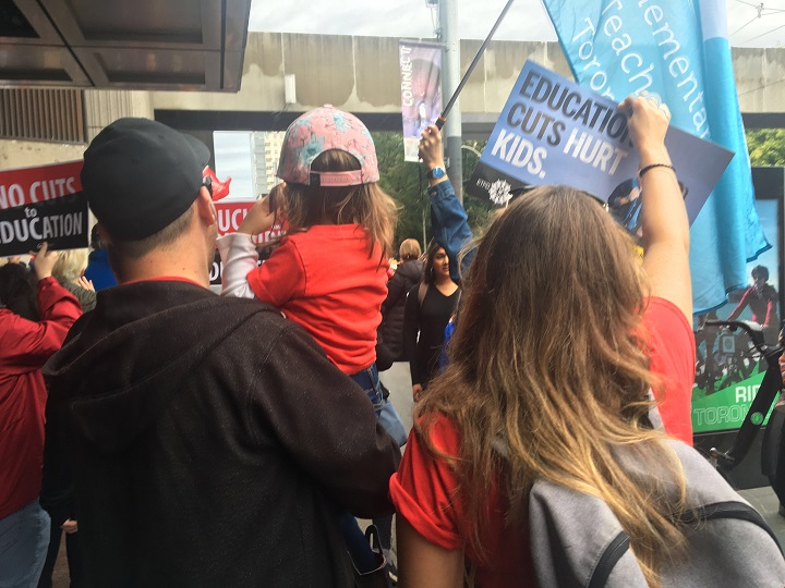Parents rally together outside the Sheraton hotel in downtown Toronto in support of CUPE workers and asking for the government to reach a settlement.