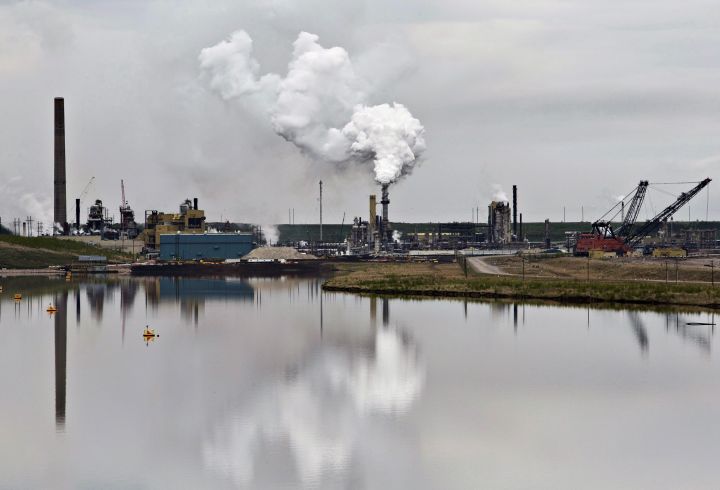 An oilsands extraction facility is reflected in a tailings pond near the city of Fort McMurray, Alberta on June 1, 2014.