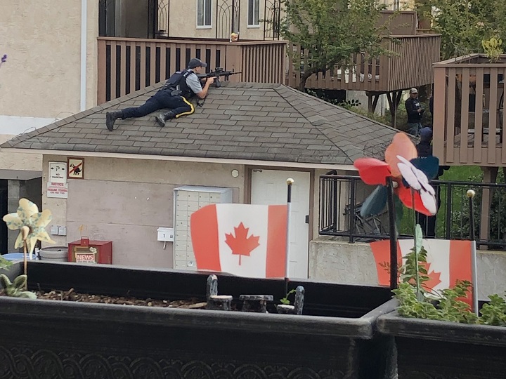 An armed police officer sits atop a roof during Wednesday’s standoff in Penticton.