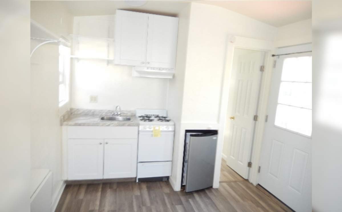 It features a small kitchenette with a bar-sized fridge and a small stove.