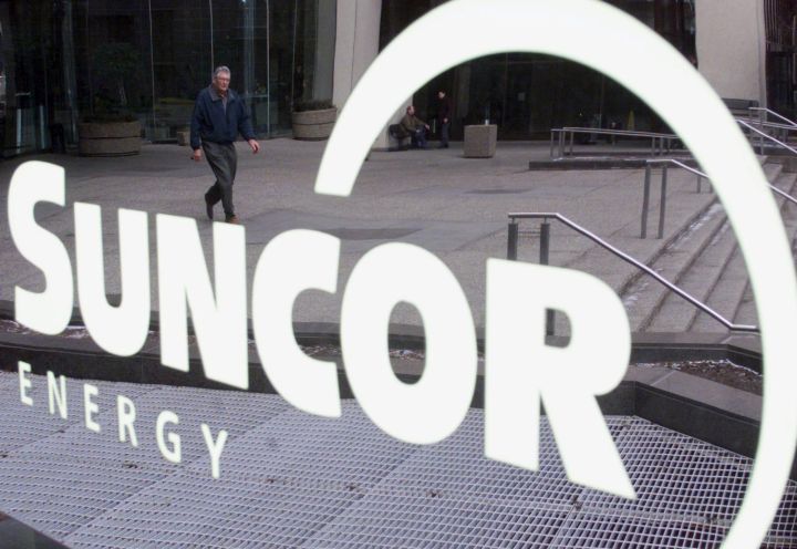 A man is reflected in a sign as he leaves the building where Suncor Energy headquarters is located in Calgary, Thursday January 17, 2002.