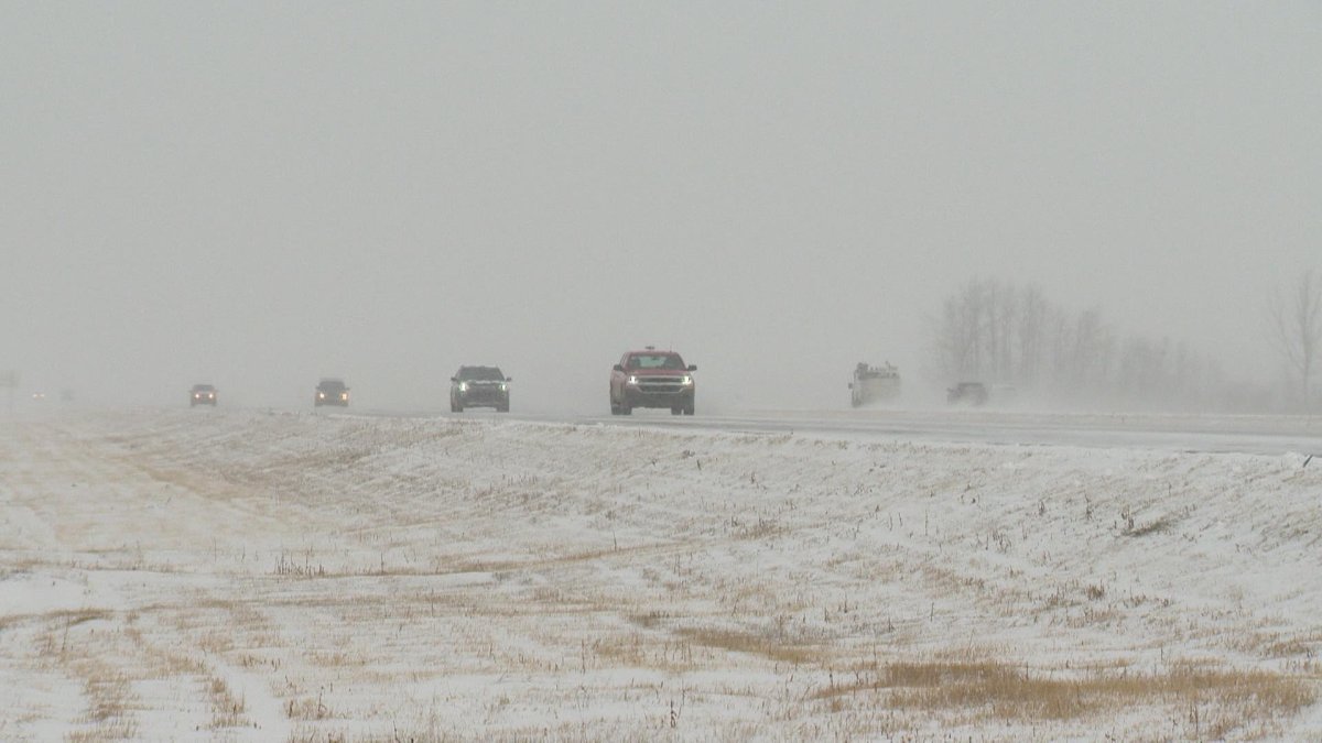 Cars drive in poor visibility on a rural highway.