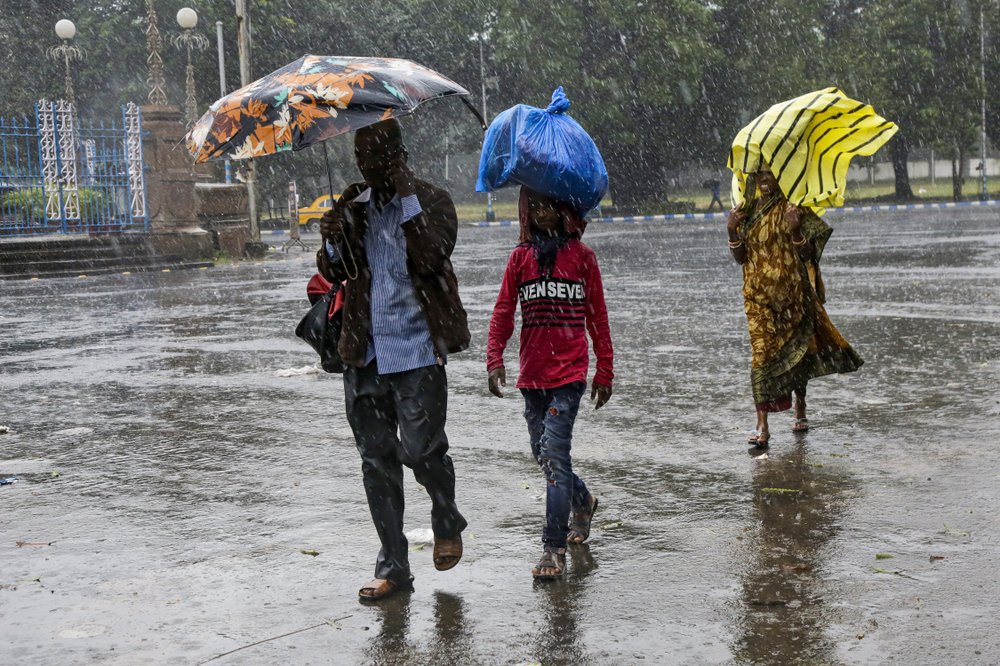 Indians walk in the rain in Kolkata, India, Saturday, Nov. 9, 2019. Authorities in nearby Bangladesh put more than 50,000 volunteers on standby and readied about 5000 shelters as a strong cyclone in the Bay of Bengal is expected to hit the low-lying nation's vast southwestern and southern coast on Saturday evening. 