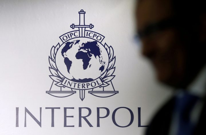 FILE PHOTO: A man passes an Interpol logo during the handing over ceremony of the new premises for Interpol's Global Complex for Innovation, a research and development facility, in Singapore September 30, 2014.