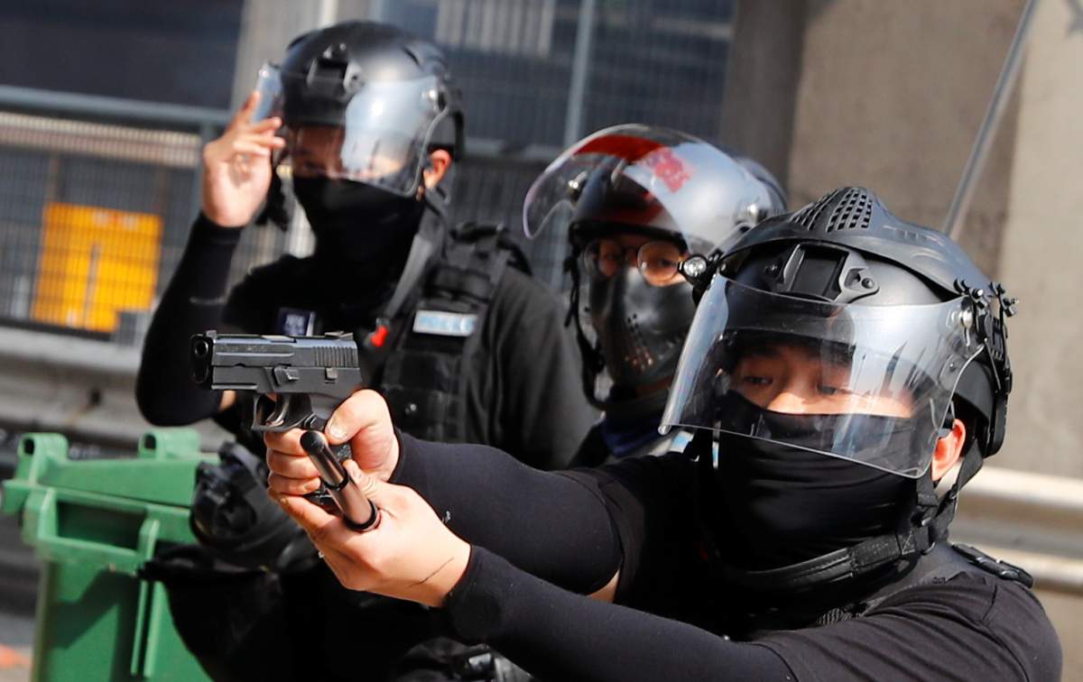 A riot police officer points a gun at protesters attempting to escape the campus of Hong Kong Polytechnic University (PolyU) during clashes with police in Hong Kong, China on Nov. 18, 2019. (REUTERS/Thomas Peter)