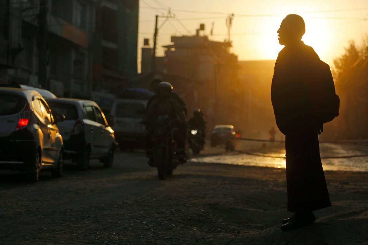 A Buddhist monk is silhouetted against the evening sun as he waits for a bus in Kathmandu, Nepal in a Feb. 21, 2019, file photo.