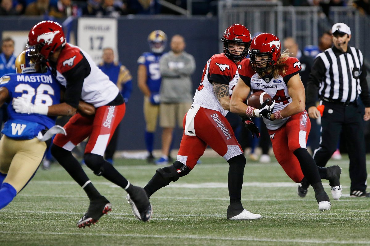 Calgary Stampeders quarterback Bo Levi Mitchell (19) hands off to Ante Milanovic-Litre (34) against the Winnipeg Blue Bombers during the first half of CFL action in Winnipeg Friday, October 25, 2019. 