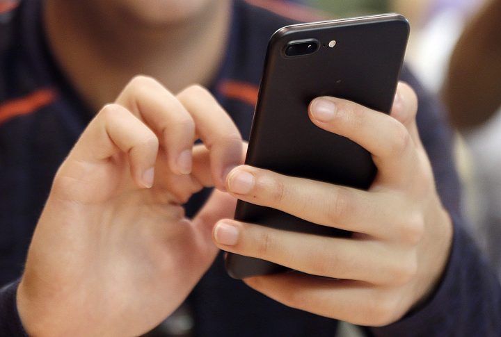 A young person uses a smart phone in Chicago. Canada's telecom companies say they're close to fully implementing new technologies they hope will combat a recent surge of spam calls, including some that pretend to be from government agencies or police. 