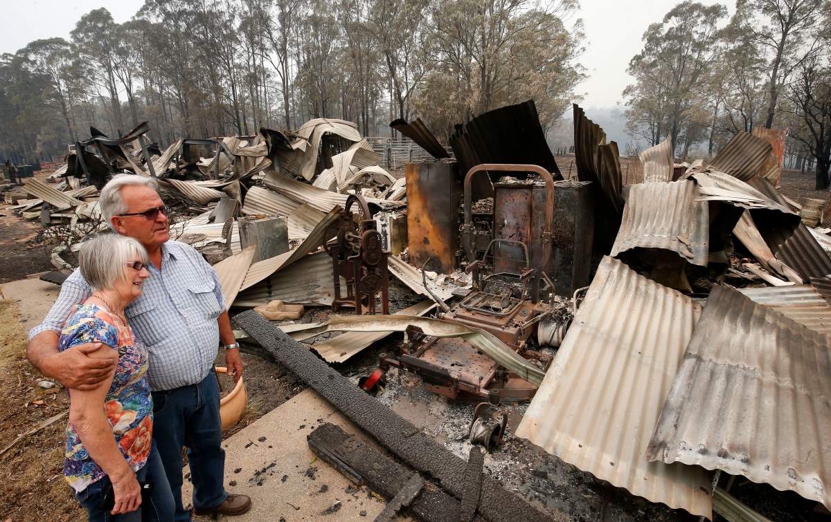 Monday, Nov. 11, 2019, Lyn and Peter Iverson watch their burnt out office and shed on their property following a bushfire at Half Chain road, Koorainghat, New South Wales state. (Darren Pateman/AAP Images via AP)