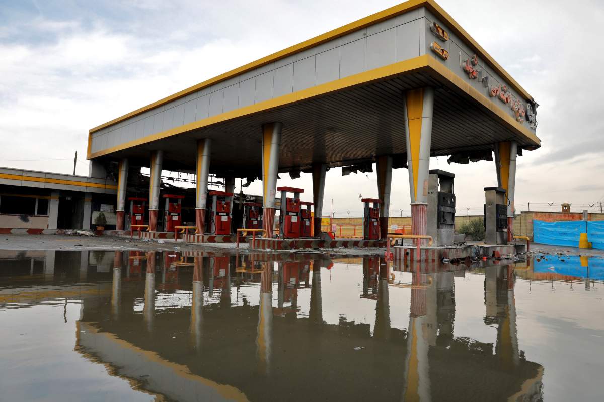 In this Nov. 20, 2019 photo, a gas station that was attacked during protests over rises in government-set gasoline prices is reflected in a puddle, in Tehran, Iran.