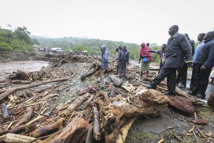 Passengers from stranded vehicles stand next to the debris from floodwaters, on the road from Kapenguria, in West Pokot county, in western Kenya Saturday, Nov. 23, 2019. Kenya's interior minister says dozens of people have been killed in mudslides, after heavy rains unleashed overnight floods in western Kenya. 