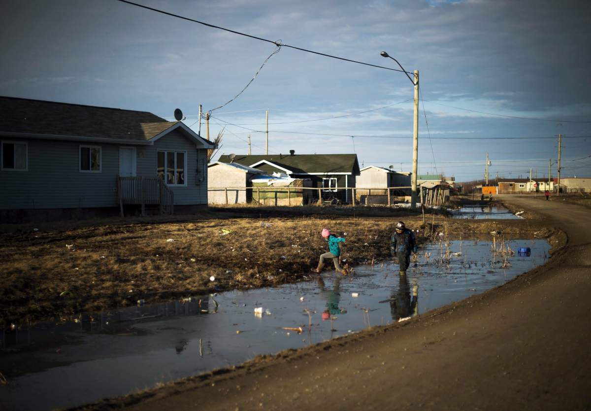 Indigenous children play in water-filled ditches in Attawapiskat, Ont. on April 19, 2016.