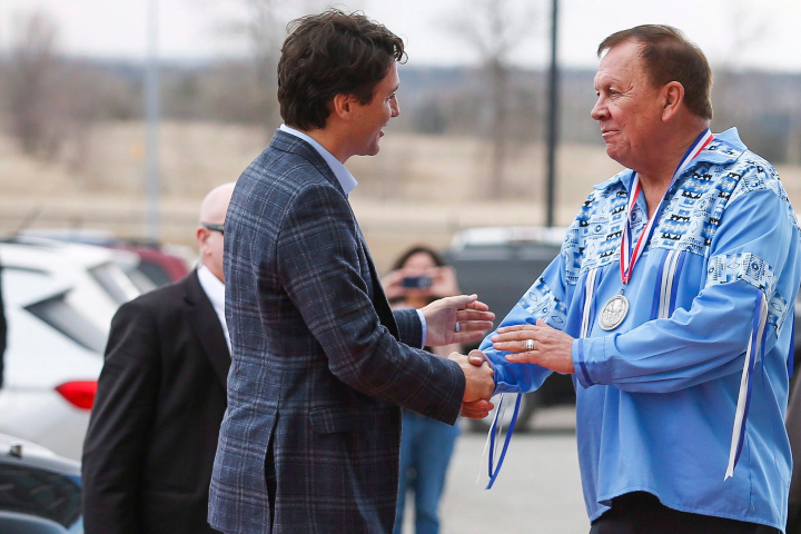 Prime Minister Justin Trudeau, left, is greeted by Roy Whitney, right, as he arrives on the Tsuut'ina First Nation near Calgary, Alta., on Friday, March 4, 2016. 