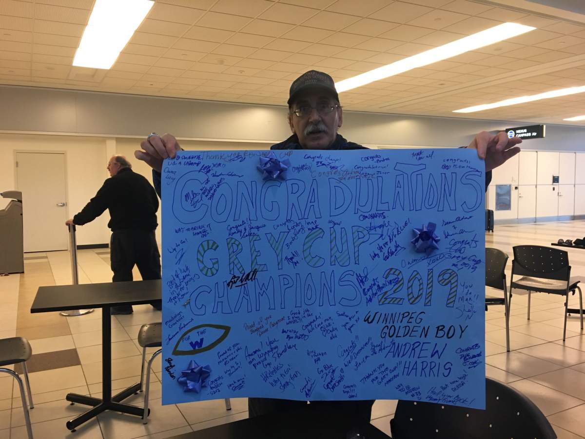 A Winnipeg Blue Bomber fans holds up a sign made to welcome the team home.