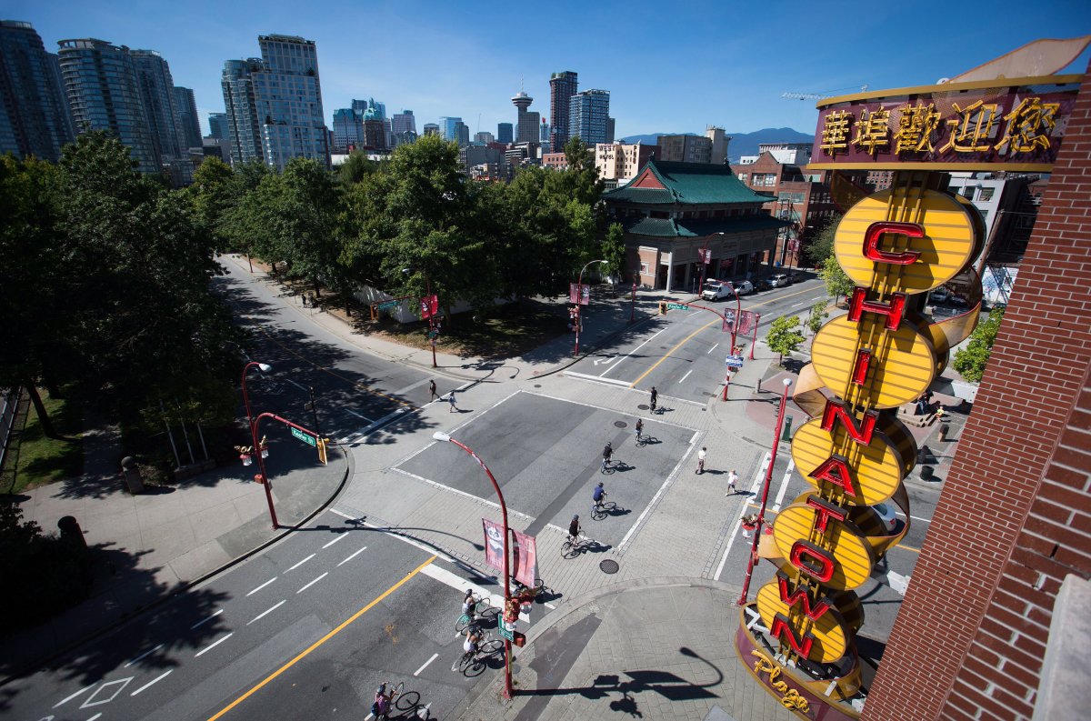 Cyclists ride past a neon Chinatown sign in Vancouver, B.C., on Thursday August 18, 2016. 