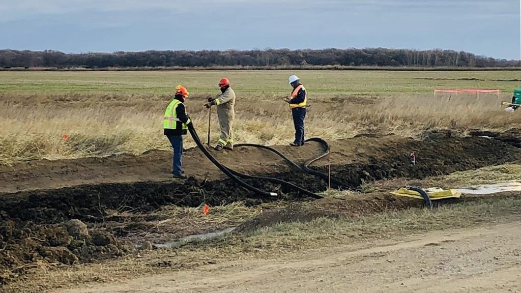 Workers survey the damage of a pipeline leak in a field near Edinburg, N.D. in this undated handout photo.