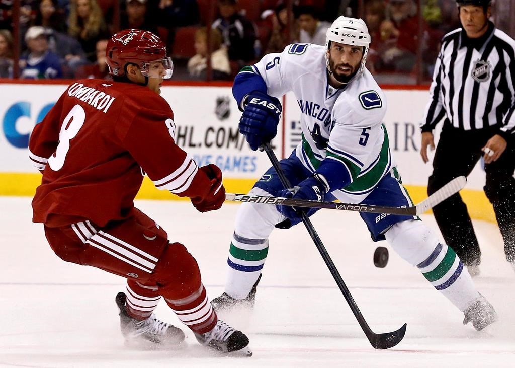 Vancouver Canucks' Jason Garrison (5) passes the puck in front of Phoenix Coyotes' Matthew Lombardi, left, during the first period in an NHL hockey game on Thursday, March 21, 2013, in Glendale, Ariz. A former National Hockey League defenceman is suing his financial adviser claiming negligent advice led to investment decisions that cost far more than the multimillion-dollar salary he earned during a six-year contract with the Vancouver Canucks.