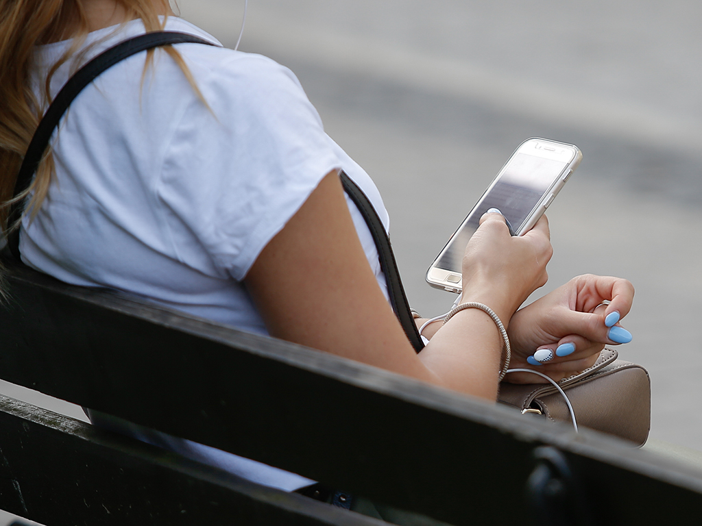 A young woman is seen using her smartphone by a tram stop on 19 August, 2017, in Bydgoszcz, Poland.