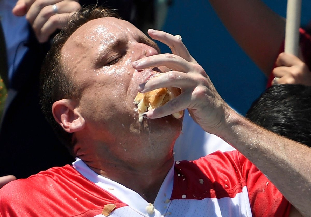 Joey Chestnut stuffs his mouth with hot dogs during the men's competition of Nathan's Famous July Fourth hot dog eating contest, Thursday, July 4, 2019, in New York's Coney Island.