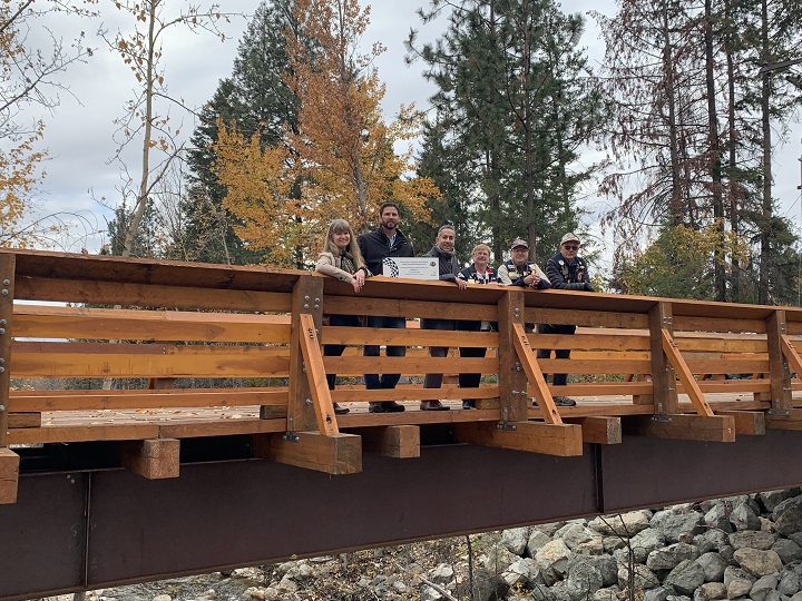 City of Kelowna employees, including mayor Colin Basran, third from left, plus members of the Kelowna Okanagan Mission Lions Club gather for a photo on the new walking and biking bridge across Bellevue Creek.