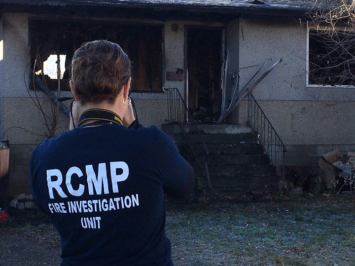 A member of the RCMP’s Fire Investigation Unit photographs the fire-damaged home.