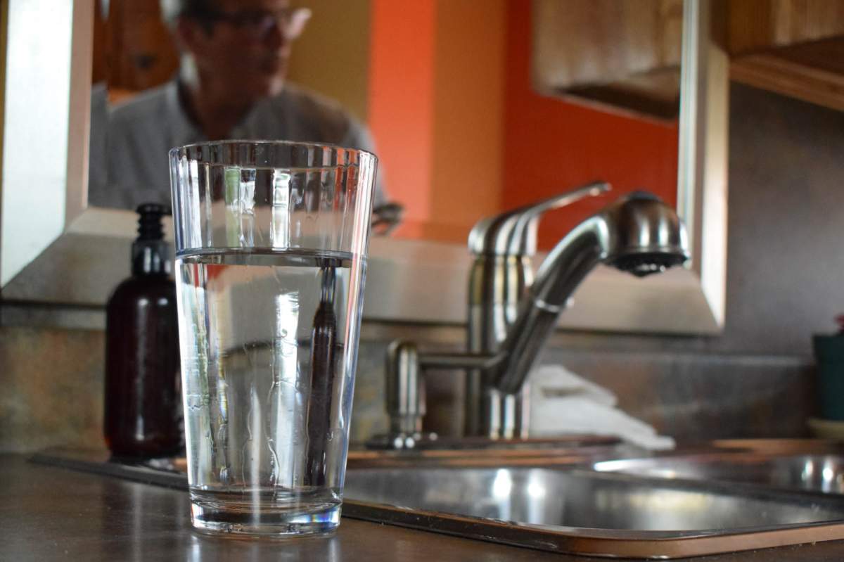 Jacques Mathurin fills a glass of water at the kitchen tap in his home in Laval, Quebec on Aug. 12, 2019. Mathurin’s water test results revealed the presence of lead in his drinking water.