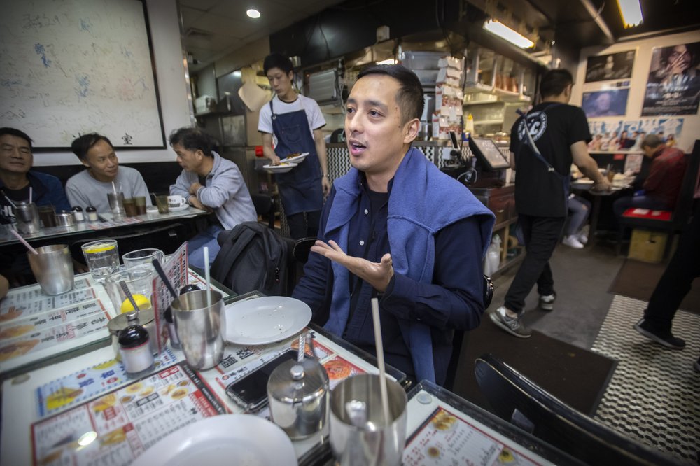 In this Dec. 13, 2019, photo, Martin Khan of Capital Cafe talks about the effects on his business after he says his store was incorrectly labeled as an anti-protest "blue" shop on online apps in Hong Kong. Protesters in Hong Kong are increasingly using their spending power to punish businesses they deem hostile to their cause. Apps are assigning color-coded labels to stores to help guide consumers. Protest-friendly stores are categorized as yellow. Blue is used to identify shops suspected of opposing protests. Protesters believe that by boycotting supposedly pro-establishment businesses, they can help shift the balance of power and wealth in the semi-autonomous Chinese territory. 