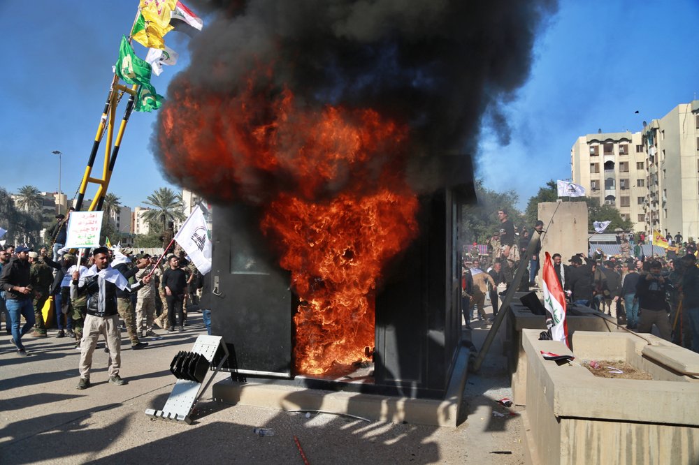 Protesters burn property in front of the U.S. embassy compound, in Baghdad, Iraq, Tuesday, Dec. 31, 2019. Dozens of angry Iraqi Shiite militia supporters broke into the U.S. Embassy compound in Baghdad on Tuesday after smashing a main door and setting fire to a reception area, prompting tear gas and sounds of gunfire.