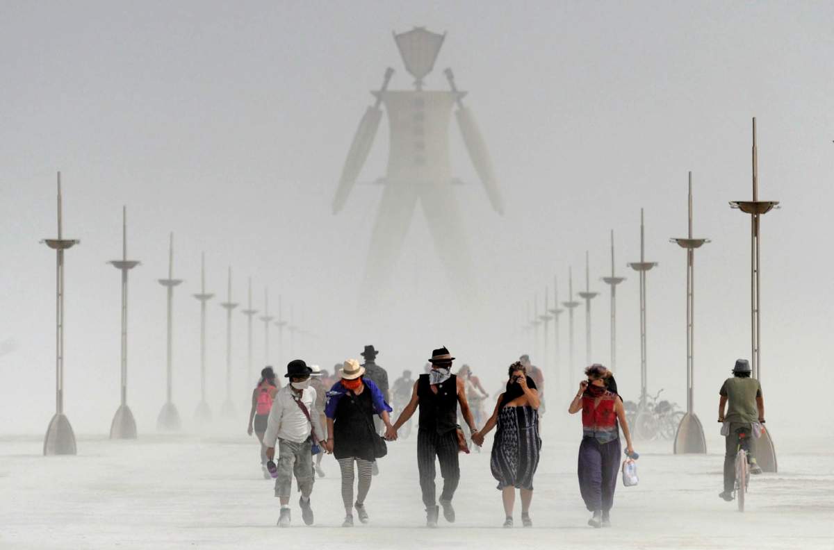 In this Aug. 29, 2014, file photo, Burning Man participants walk through dust at the annual Burning Man event on the Black Rock Desert of Gerlach, Nev.