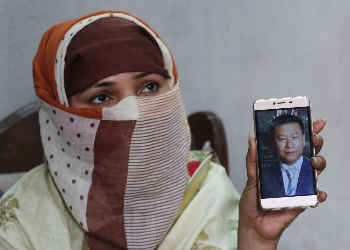 In this May 22, 2019 photo, Sumaira a Pakistani woman, shows a picture of her Chinese husband in Gujranwala, Pakistan.