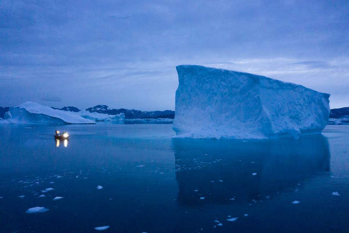 In this Aug. 15, 2019, file photo, a boat navigates at night next to large icebergs in eastern Greenland.