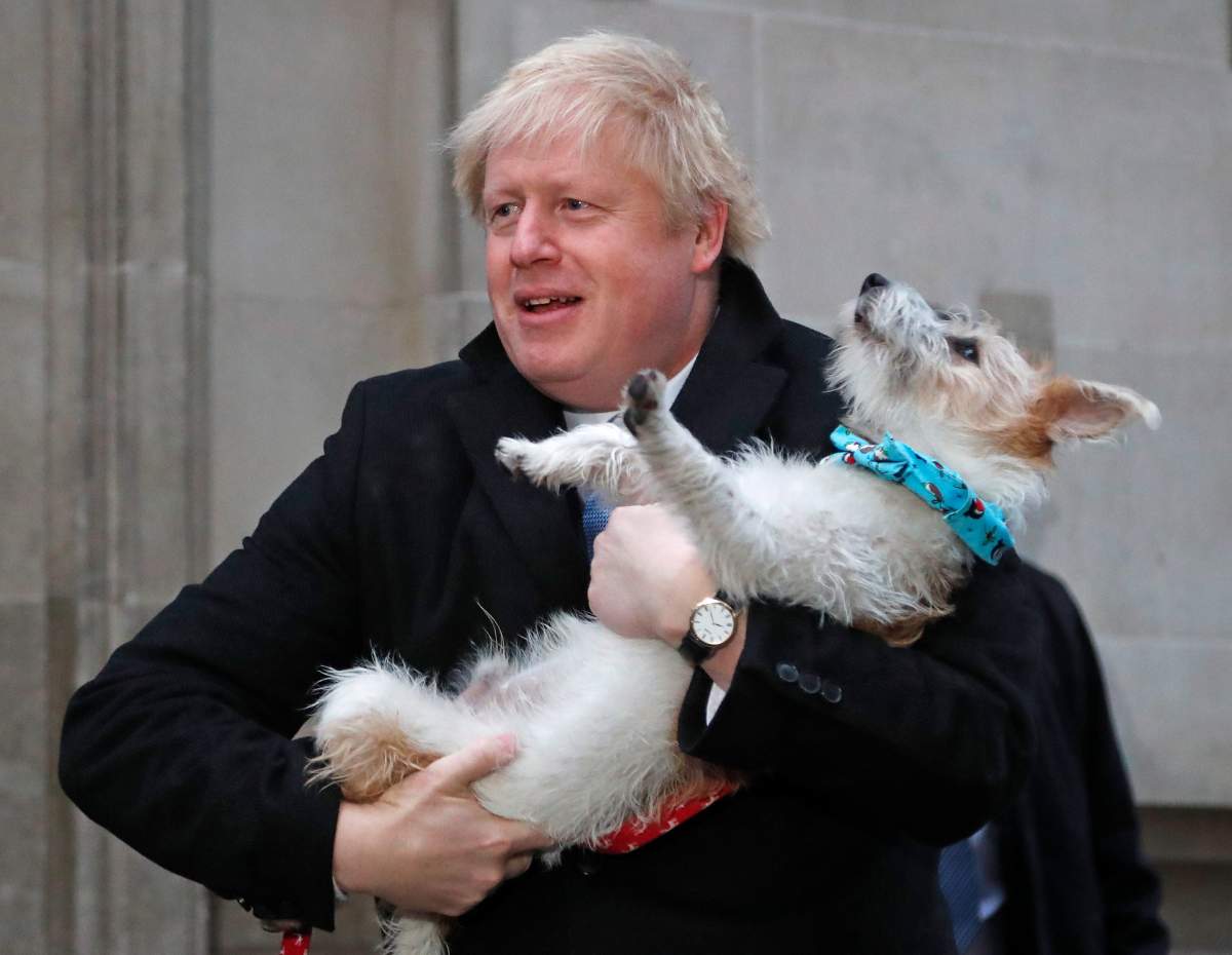 Britain’s Prime Minister and Conservative Party leader Boris Johnson holds his dog Dilyn as he leaves after voting in the general election at Methodist Central Hall, Westminster, London, Thursday, Dec. 12, 2019.