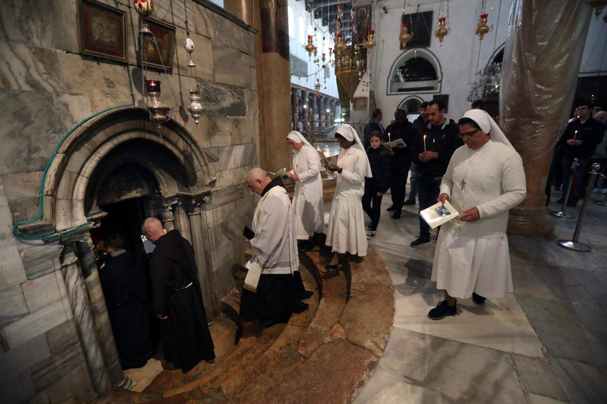 Priests pray during a mass at the Holy Cave in the Church of Nativity in the West Bank town of Bethlehem, 17 December 2019.