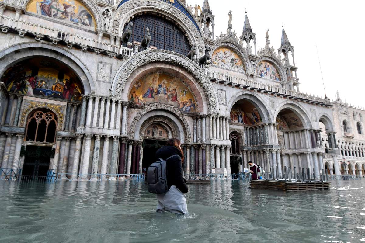 A woman wades through water during a high tide of 1.44 meters (4.72 feet), in St. Mark’s Square, in Venice, Italy, Monday, Dec. 23, 2019.