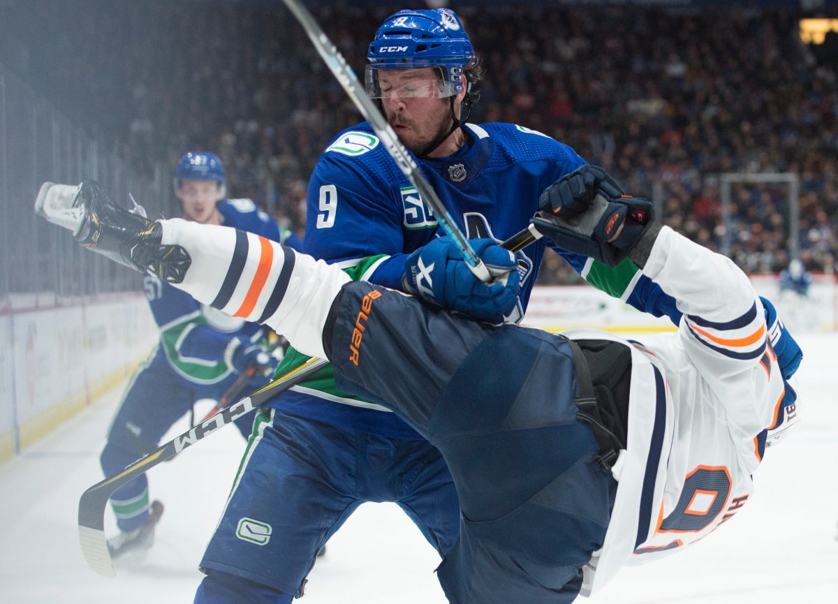 Vancouver Canucks center J.T. Miller (9) fights for control of the puck with Edmonton Oilers center Gaetan Haas (91) during second period NHL action in Vancouver on Monday, December, 23, 2019. THE CANADIAN PRESS/Jonathan Hayward.