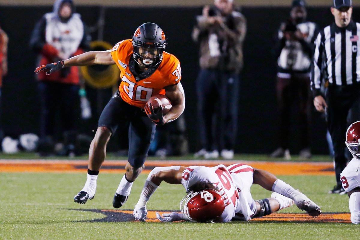 Oklahoma State running back Chuba Hubbard (30) avoids a tackle by Oklahoma linebacker Caleb Kelly (19) in the first half of an NCAA college football game in Stillwater, Okla., Saturday, Nov. 30, 2019. 