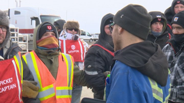 Truck driver Mike Schick faces a barricade of picketing Co-op Refinery workers while trying to leave the complex.
